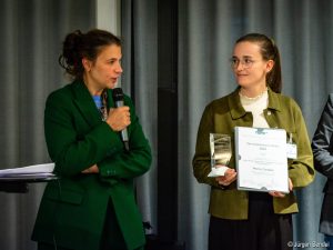 Eine Frau übergibt den Vera-Damman-Preis 2025 an die erste Preisträgerin